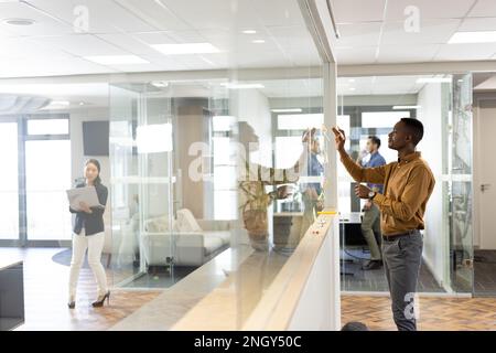 African american man in office brainstorming and writing on glass board Stock Photo