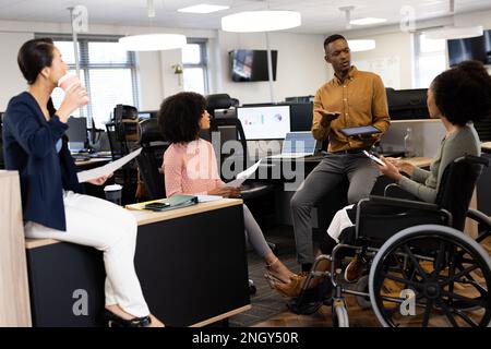 Diverse businesspeople in office talking and laughing Stock Photo