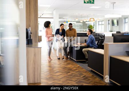 Diverse businesspeople in office talking and laughing Stock Photo