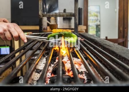 Chef turning food over coals smoldering in grill Stock Photo