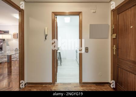 Distributor hall of a residential house with wooden floors, access to a fitted kitchen and a living room with a glass dining table Stock Photo