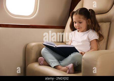 A girl reading a book in the plane with a beautiful view of mountains and clouds from the porthole Stock Photo - Alamy