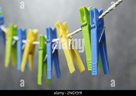 Green plastic clothespins on rope against grey background, closeup Stock Photo
