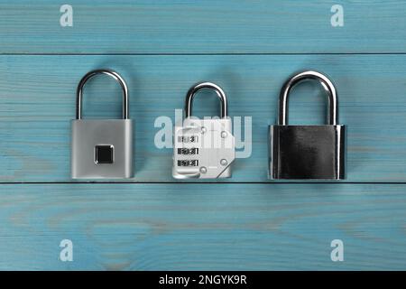 Different padlocks on light blue wooden table, flat lay Stock Photo