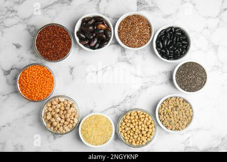 Frame of different grains and seeds with space for text on white marble table, flat lay. Veggie diet Stock Photo