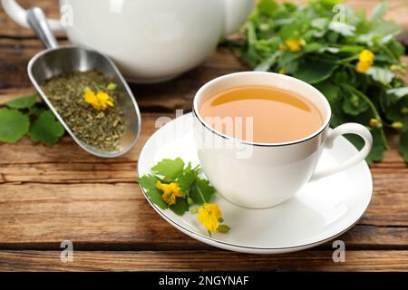 Cup of aromatic celandine tea and flowers on wooden table Stock Photo