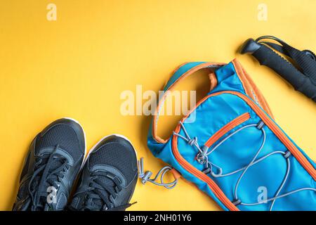Sports shoes, hiking stick and back pack. Sports or hiking concept. On yellow background, copy space. Stock Photo