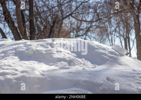Landscape view of a mound of white snow, just beginning to melt under natural sunlight in late winter Stock Photo