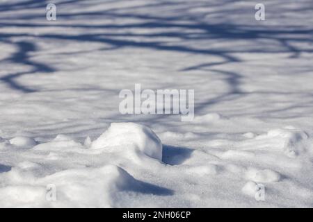Landscape view of a mound of white snow, just beginning to melt under natural sunlight in late winter Stock Photo