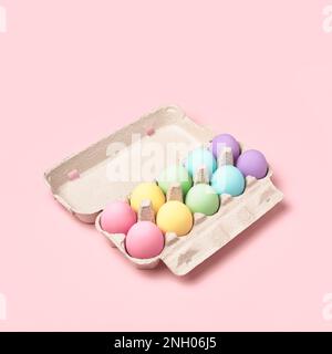 Pastel colored Easter Eggs in egg box on pink background. Rainbow, minimal style. Easter greeting card. Stock Photo