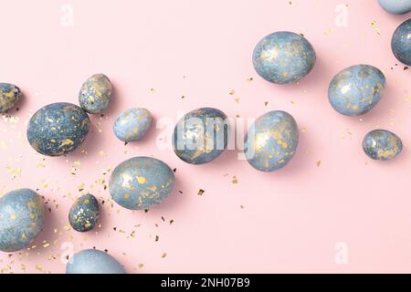 Blue Easter eggs on pink background with gold confetti. Chic Easter greeting card. Easter celebration. Stock Photo