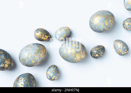 Blue Easter eggs with golden spots on light blue Easter background. Chic Easter greeting card, flat lay, Diagonal composition. Stock Photo
