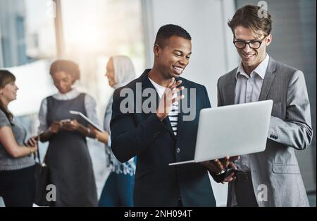 The team doing what they do best. a group of young cheerful businesspeople browsing on digital devices while working together in the office at work. Stock Photo