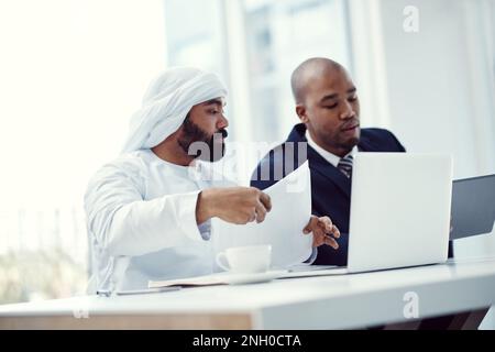 Effective collaboration is the foundation of a successful company. two businessmen using a digital tablet and laptop while having a discussion in a Stock Photo