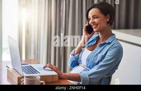 Her company provides flexible working hours during pregnancy. a pregnant young woman using a laptop and mobile phone while working from home. Stock Photo