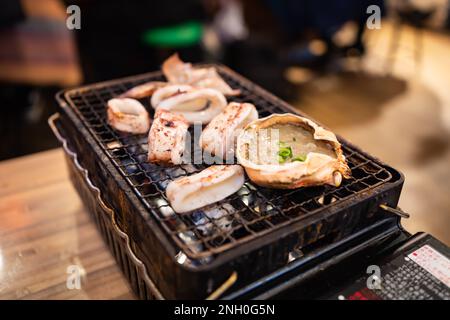 Kani Miso and baked squid on a grill Stock Photo