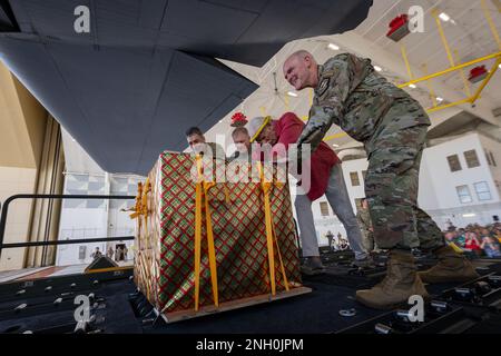 (Right to left) Col. Kyle Benwitz, 515th Air Mobility Operations Wing commander, Bruce Best, University of Guam researcher, Brig. Gen. Paul Birch, 36th Wing commander, and Col. Andrew Roddan, 374th Airlift Wing commander, push a box of humanitarian goods into a C-130J Super Hercules assigned to the 36th Expeditionary Airlift Squadron during the Operation Christmas Drop push ceremony at Andersen Air Force Base, Guam, Dec. 5, 2022. Operation Christmas Drop is an annual event that delivers aid to island communities in the Northern Mariana Islands, the Federated States of Micronesia, and the Repub Stock Photo