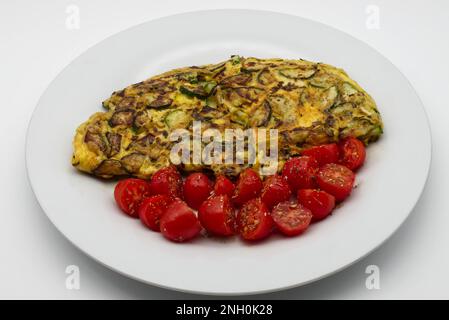 Omelette with zucchini and cherry tomatoes isolated on white background. Stock Photo