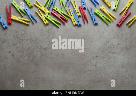 Colorful plastic clothespins on grey stone background, flat lay. Space for text Stock Photo
