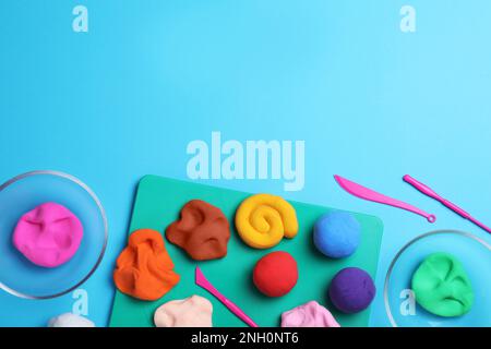 Flat lay composition with colorful plasticine on light blue background. Space for text Stock Photo