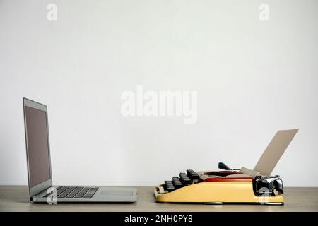 Old typewriter and laptop on table against light background, space for text. Concept of technology progress Stock Photo