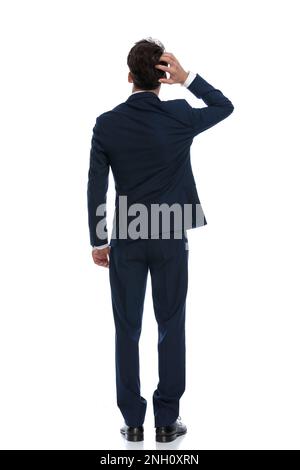 attractive businessman scratching head and pondering, wearing a suit and tie against white background Stock Photo