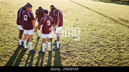 Men, huddle and team holding hands praying on grass field for sports coordination or collaboration outdoors. Group of sport players in fitness Stock Photo