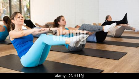 People of different ages in sportswear developing core muscles during Pilates training in rehabilitation center Stock Photo