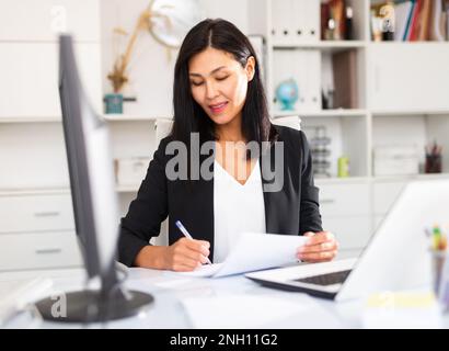 Young asian woman working in office and signs documents Stock Photo