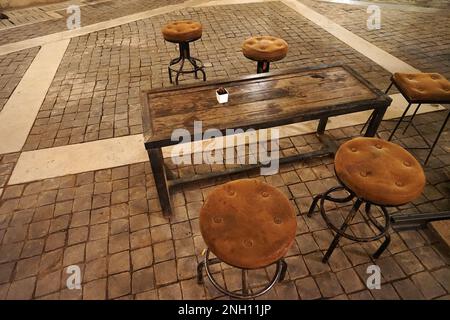 Suede leather stool chairs with antique wooden table Stock Photo