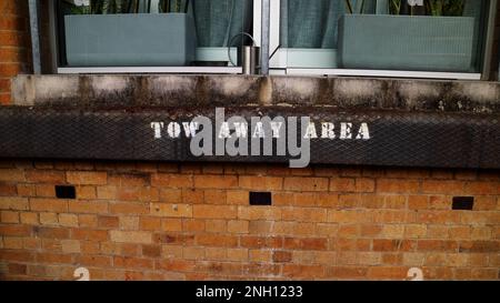 Tow away area sign painted on a wall of apartment building Stock Photo