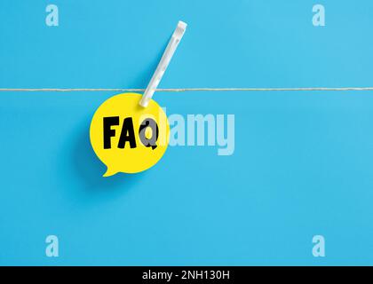 The acronym FAQ frequently asked questions on a speech bubble hanging on clothesline with a clothespin. Stock Photo