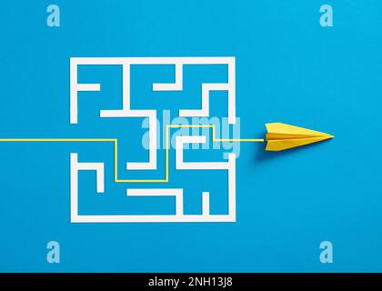 Overcoming the barriers. Conquering the obstacles. Way to success and business solutions. Exit strategy. Paper plane breaking through the maze on blue Stock Photo