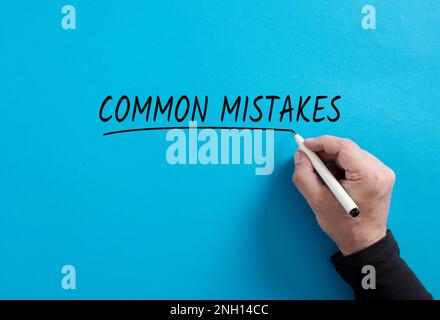 Male hand underlines the word Common Mistakes on blue background. Business or education concept for common decision mistakes. Stock Photo