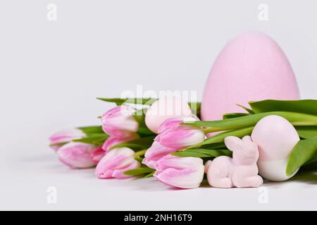 Easter arrangement with tulip flowers, pink easter bunny and painted eggs Stock Photo