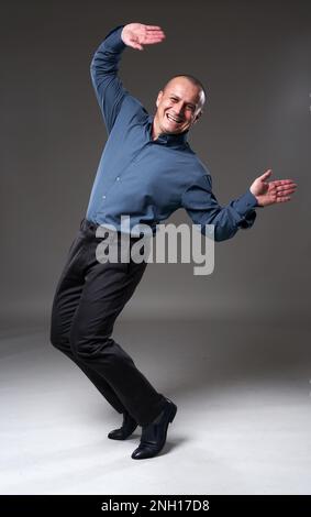 Exhilarated successful happy businessman dancing, celebrating victory, full body shot on gray background Stock Photo