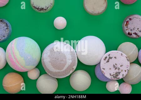 Multicolored bath bombs on a green background, top view. Stock Photo