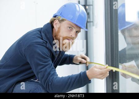 young engineer with safety helmet measuring window Stock Photo