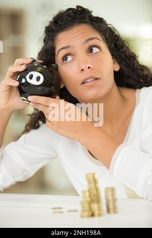 young unhappy woman emptying her piggybank savings Stock Photo