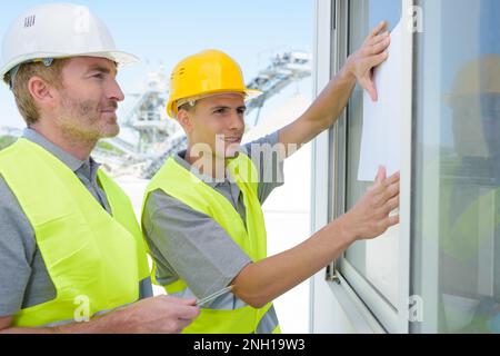 two construction workers securing window Stock Photo