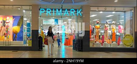 Primark clothing store entrance back view of customers beside window displays at indoor shopping mall Lakeside retail centre Thurrock Essex England UK Stock Photo