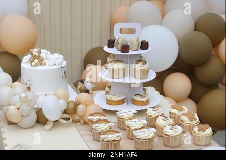 Creative gender neutral baby shower or birthday decoration in the garden. Bohemian style outdoor event set up with balloons. White cream peach caramel Stock Photo