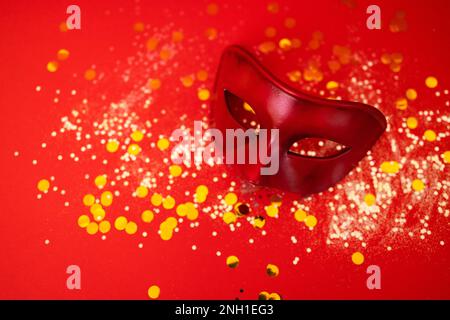 Beautiful carnival or masquerade mask lies on a red background with gold round confetti and silver glitters. Great for invitations or presentations. F Stock Photo