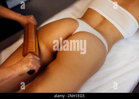 Massage madera. Maderotherapy anti cellulite massage treatment with wooden prop, female leg calves in a wellness center Stock Photo