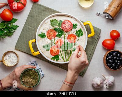 the girl sprinkles spices with homemade bread with vegetables. f Stock Photo