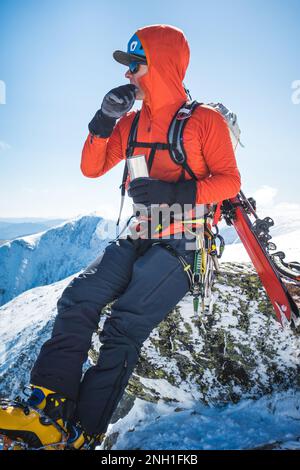 Ski mountaineer taking a break and drinking a hot beverage Stock Photo