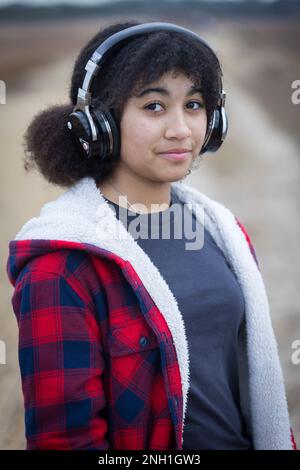 biracial teen girl wearing headphones with serious expression Stock Photo