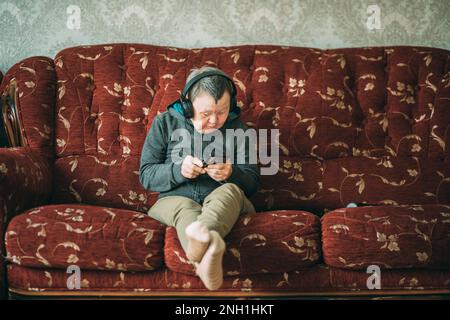 elderly woman with down syndrome with smartphone and headphones Stock Photo