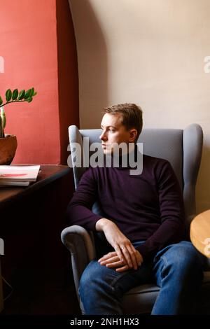 young man sits alone at a table with magazines Stock Photo