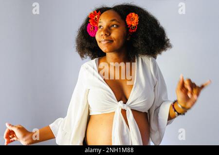 Top-half of pregnant woman dancing with flowers in hair Stock Photo